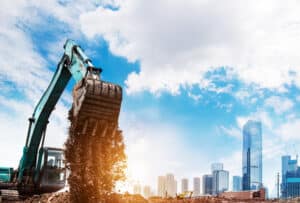 an excavator digging dirt in front of a city skyline