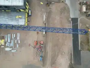 Overhead drone view of a tower crane jib and steel materials on a site