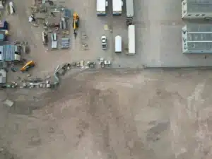 Aerial drone view of a construction staging yard with trailers, lifts and materials