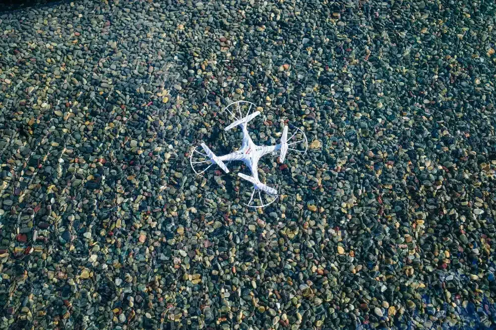 Features of drone mapping systems: Drone Mapping Software and Key Use Cases 12 White drone resting on colorful river gravel
